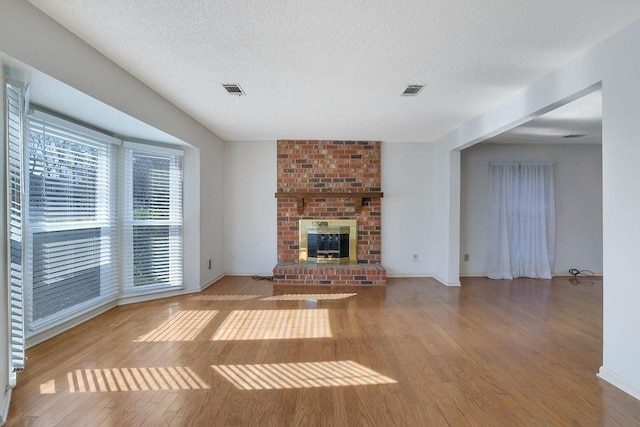 unfurnished living room with wood-type flooring, a fireplace, and a textured ceiling