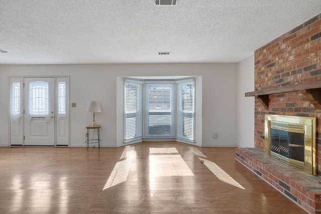 unfurnished living room featuring hardwood / wood-style flooring, a fireplace, and a textured ceiling