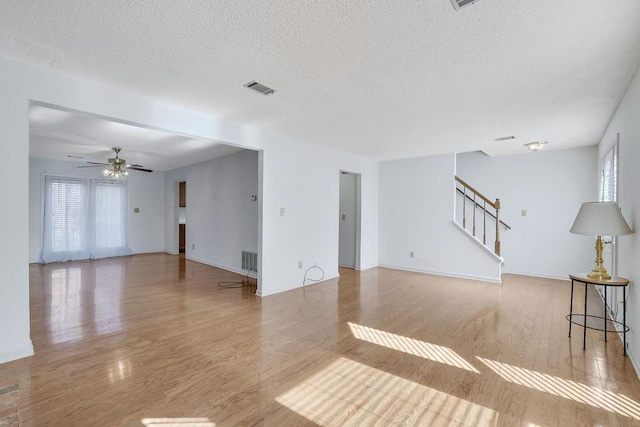 unfurnished living room with ceiling fan, a healthy amount of sunlight, a textured ceiling, and light wood-type flooring