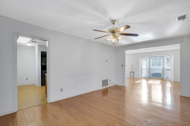 spare room with ceiling fan, light hardwood / wood-style floors, and a textured ceiling