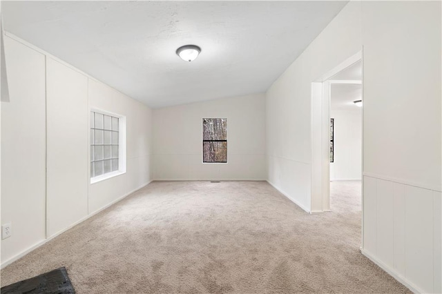 carpeted spare room featuring vaulted ceiling