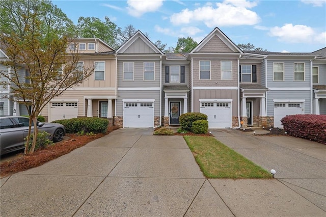 townhome / multi-family property featuring driveway, board and batten siding, stone siding, and an attached garage