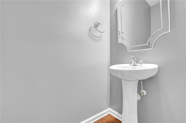 bathroom featuring baseboards, a sink, and wood finished floors