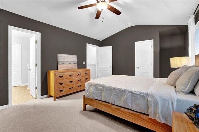 bedroom with ensuite bathroom, a ceiling fan, light carpet, lofted ceiling, and baseboards