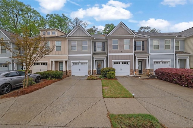 multi unit property with a garage, driveway, board and batten siding, and stone siding