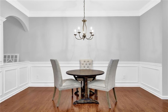 dining area featuring a chandelier, crown molding, and wood finished floors