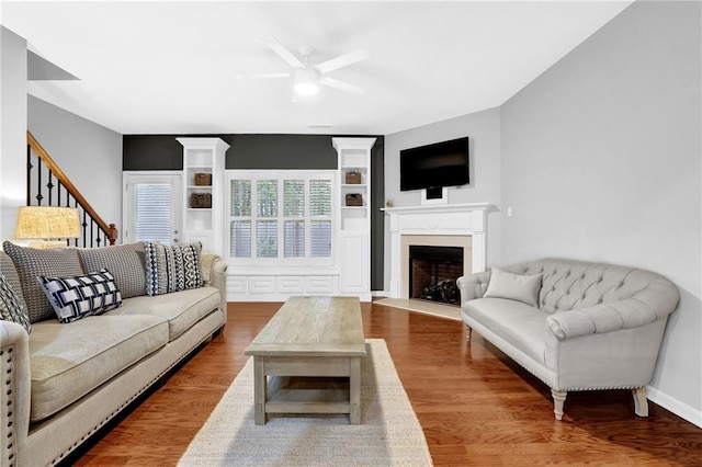 living area with a fireplace with flush hearth, wood finished floors, and ceiling fan