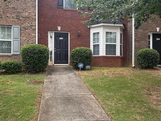 view of exterior entry featuring a lawn