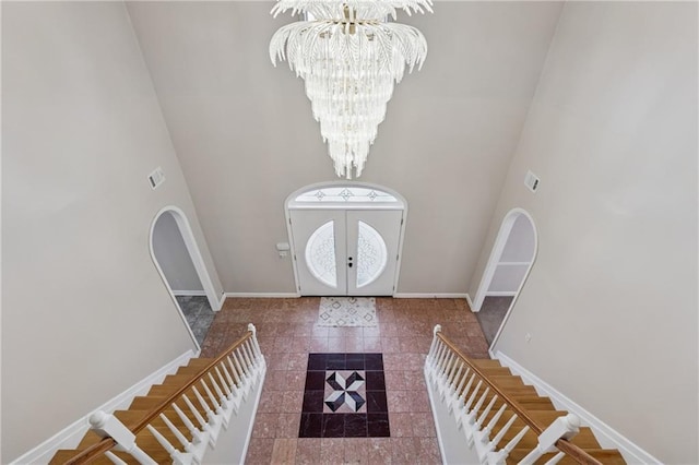 foyer featuring stairway, baseboards, and a chandelier