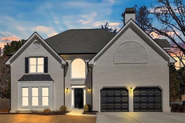 traditional-style home with concrete driveway, brick siding, a chimney, and roof with shingles