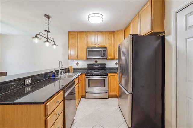 kitchen with tasteful backsplash, appliances with stainless steel finishes, dark stone countertops, a peninsula, and a sink