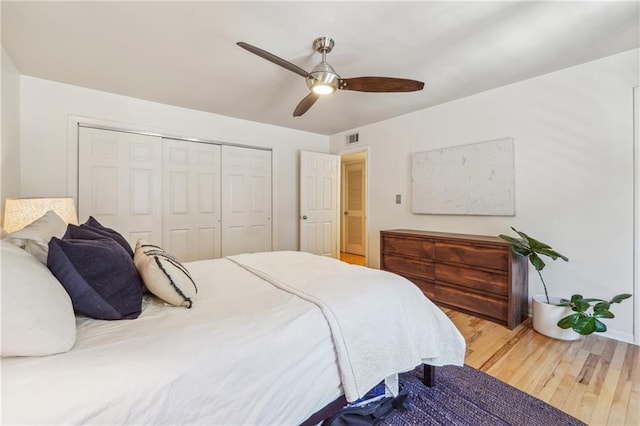 bedroom featuring a ceiling fan, a closet, visible vents, and wood finished floors