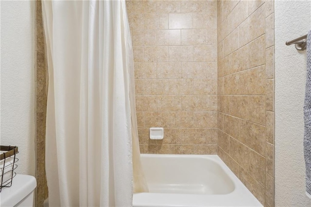 full bathroom with a textured wall and toilet