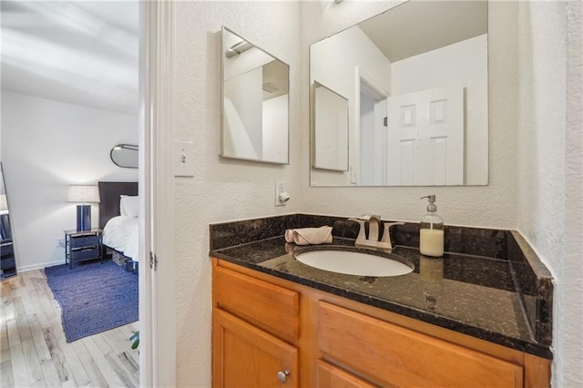 bathroom with baseboards, a textured wall, wood finished floors, ensuite bathroom, and vanity