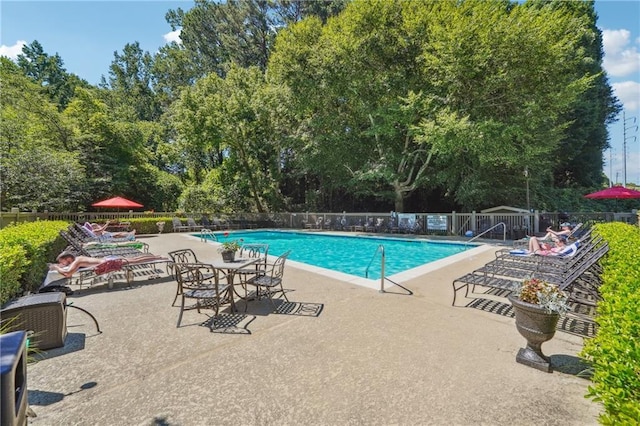 community pool with a patio and fence