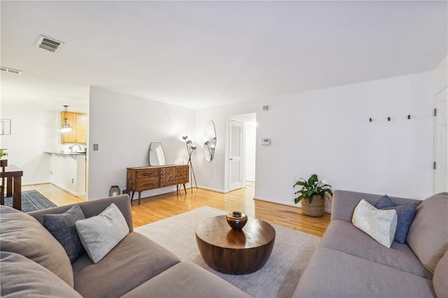 living area with light wood-type flooring, visible vents, and baseboards