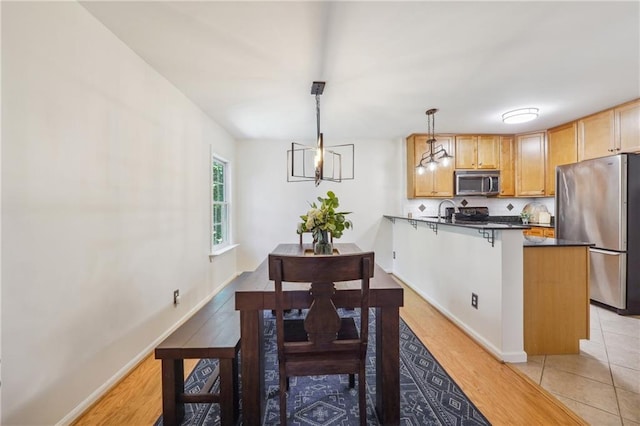 dining room featuring baseboards, an inviting chandelier, and light wood-style floors