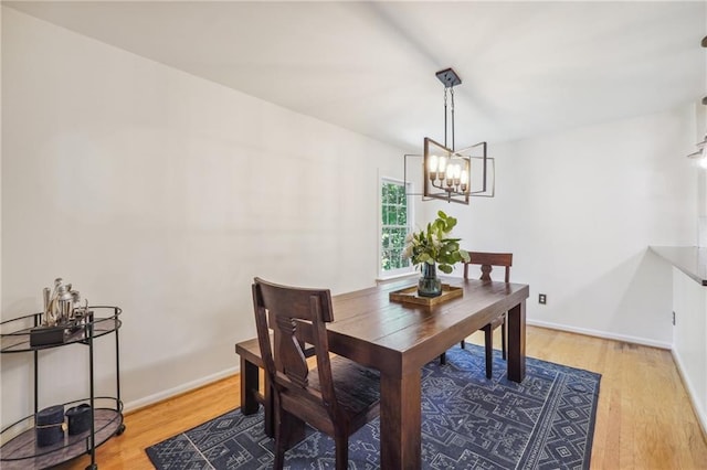 dining area with baseboards, light wood-style flooring, and a notable chandelier