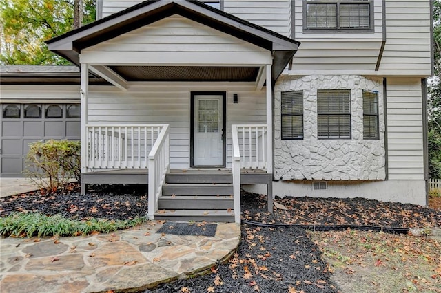 view of exterior entry featuring a garage and covered porch