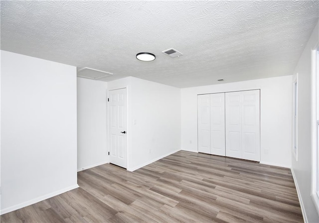 unfurnished bedroom featuring hardwood / wood-style flooring, a textured ceiling, and a closet