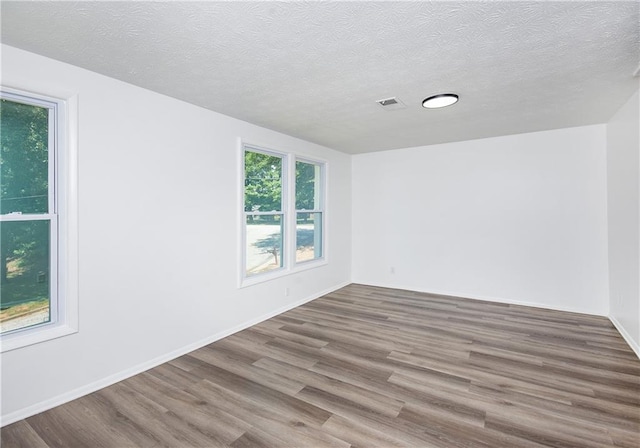 empty room with a textured ceiling and hardwood / wood-style flooring