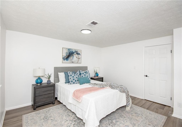 bedroom featuring wood-type flooring and a textured ceiling