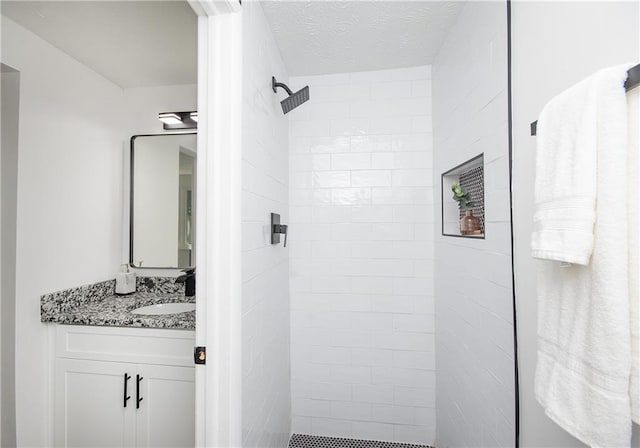 bathroom featuring a tile shower, vanity, and a textured ceiling