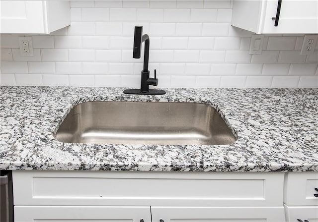 room details with white cabinets, tasteful backsplash, and sink