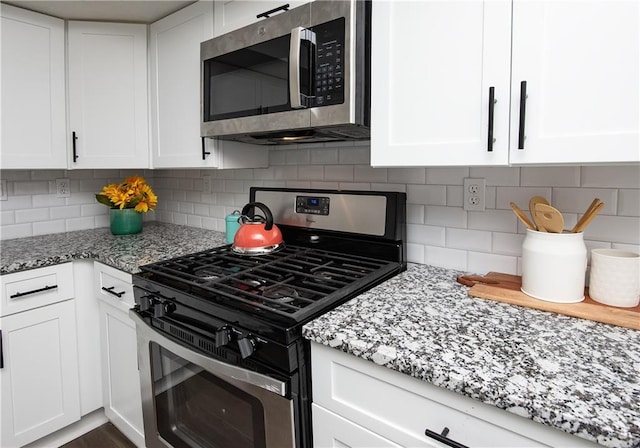 kitchen with white cabinets, light stone counters, backsplash, and appliances with stainless steel finishes