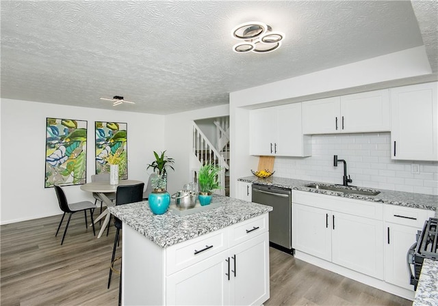 kitchen with white cabinets, tasteful backsplash, sink, dishwasher, and a center island