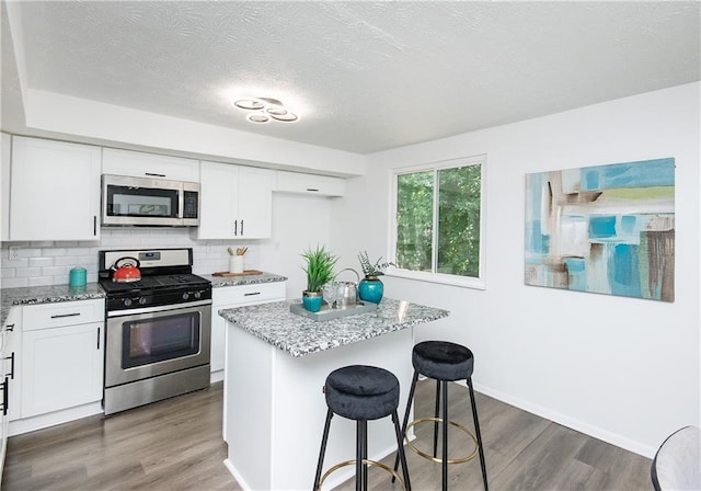 kitchen featuring light stone counters, a center island, white cabinets, and stainless steel appliances