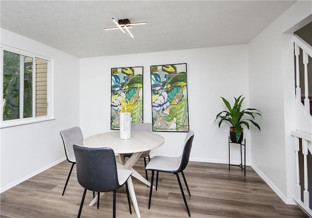 dining space with a textured ceiling and hardwood / wood-style flooring