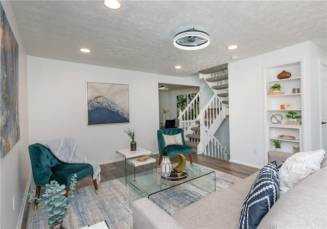 living room featuring built in shelves, hardwood / wood-style floors, and a textured ceiling