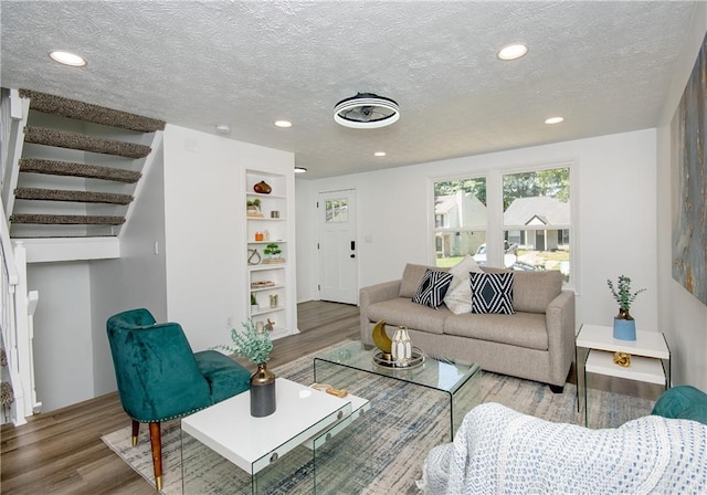 living room featuring built in features, a textured ceiling, and hardwood / wood-style flooring