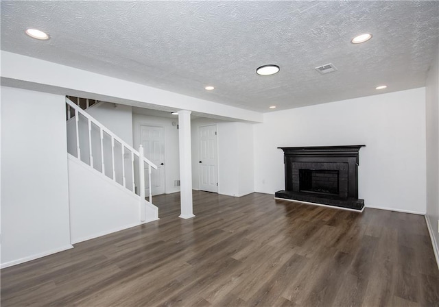 basement with dark hardwood / wood-style flooring, a textured ceiling, and a brick fireplace