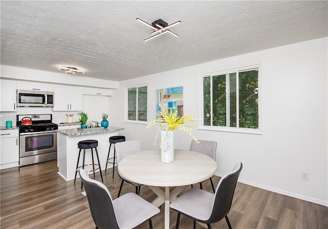 dining room with wood-type flooring and a textured ceiling