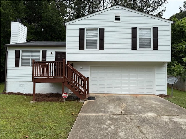 tri-level home featuring an attached garage, driveway, a chimney, and a front yard
