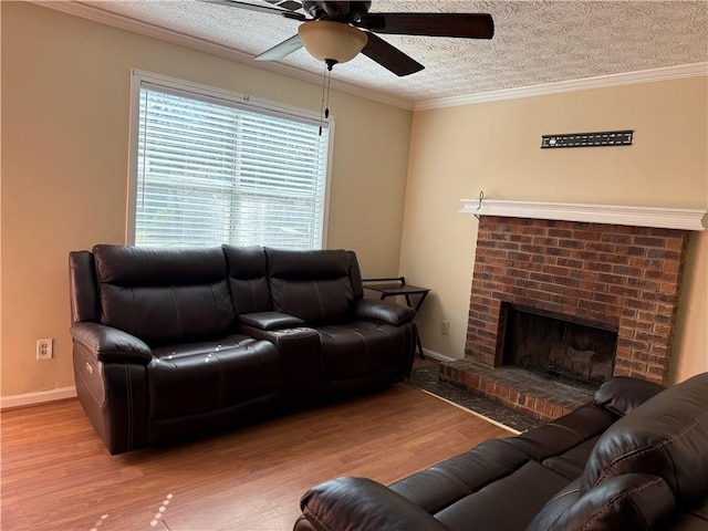 living room featuring a ceiling fan, a textured ceiling, a brick fireplace, wood finished floors, and baseboards