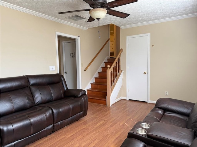 living area with a ceiling fan, a textured ceiling, visible vents, stairway, and light wood finished floors