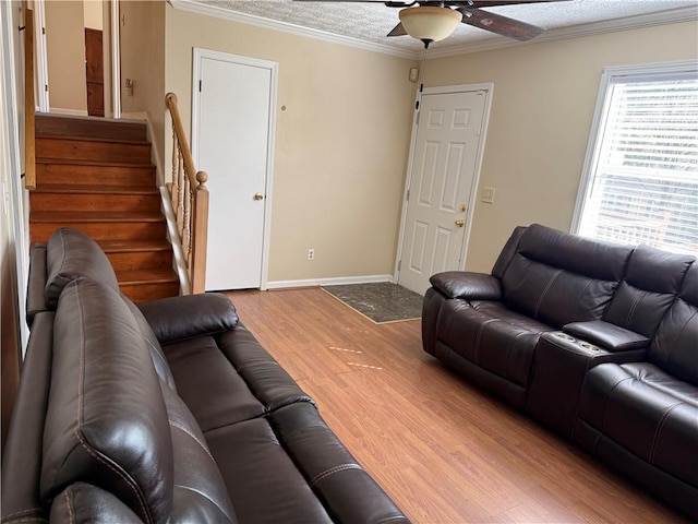 living area featuring ceiling fan, crown molding, stairway, baseboards, and light wood finished floors