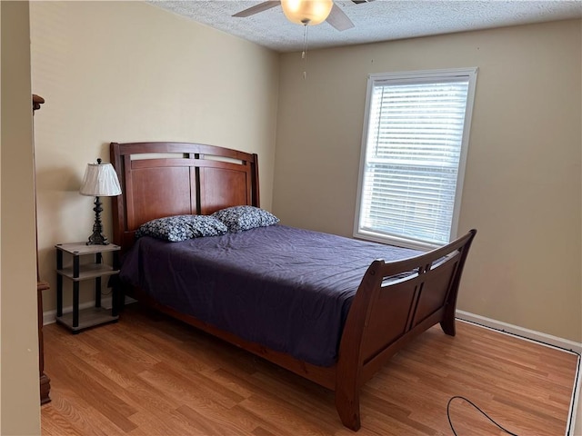 bedroom with baseboards, ceiling fan, a textured ceiling, and wood finished floors