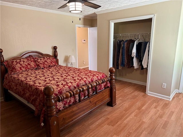 bedroom featuring crown molding, a textured ceiling, wood finished floors, a spacious closet, and a closet