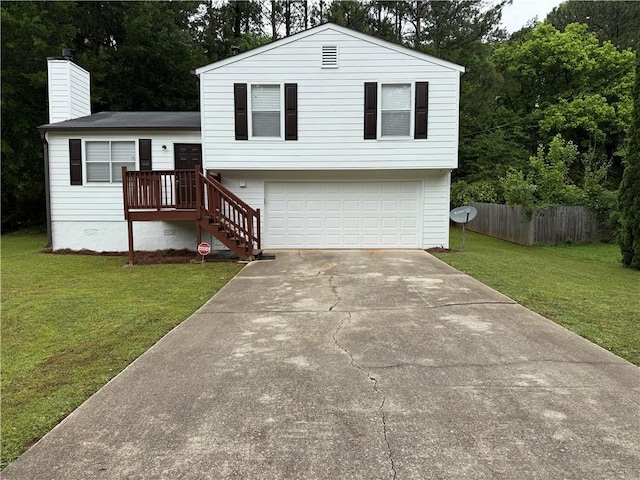 split level home with a garage, fence, a front yard, a chimney, and driveway