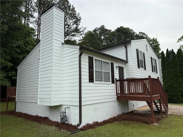 view of side of property featuring stairs, a wooden deck, a chimney, and a yard