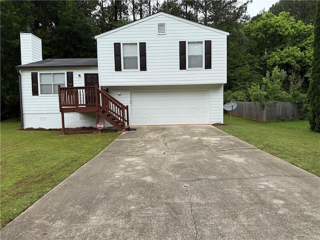 tri-level home with fence, a front yard, a chimney, an attached garage, and driveway