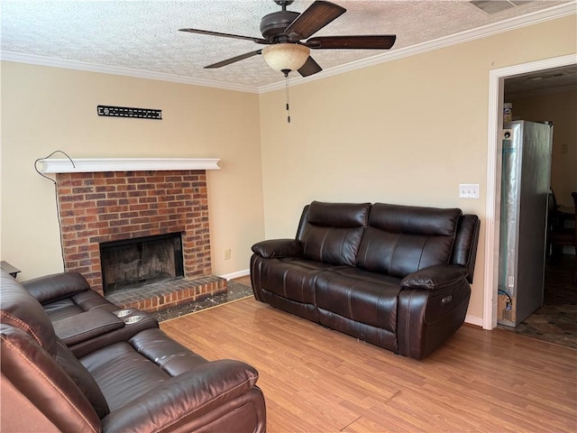 living area with crown molding, ceiling fan, a fireplace, a textured ceiling, and wood finished floors