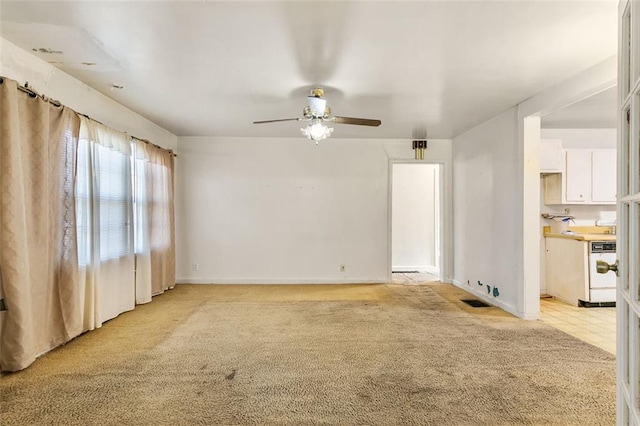 empty room featuring light carpet, visible vents, baseboards, and a ceiling fan