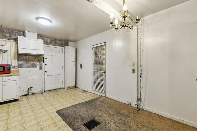 kitchen featuring light floors, visible vents, an inviting chandelier, white cabinets, and baseboards