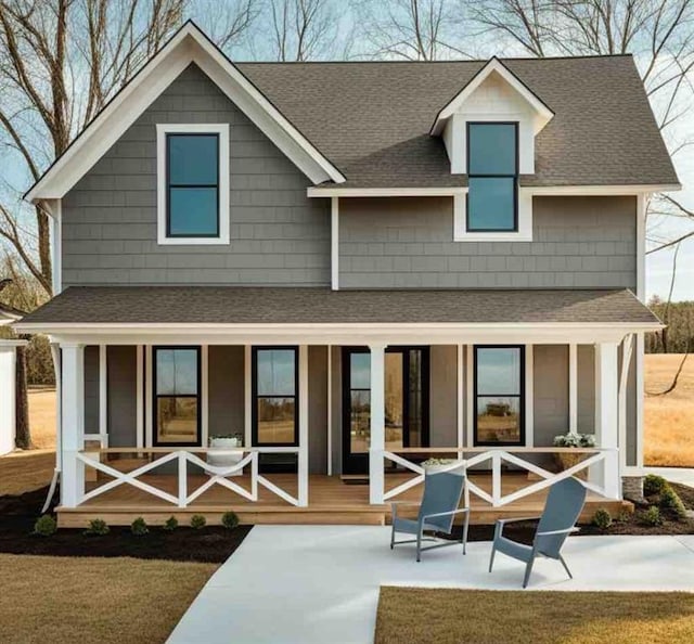 back of house featuring a yard, a porch, and roof with shingles