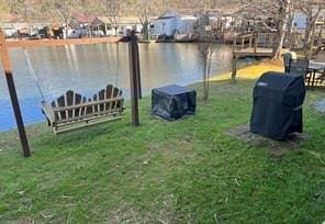 view of dock with a water view and a lawn